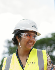 Woman wearing construction hat and vest, smiling